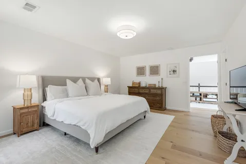 a spacious bedroom with a bed a couch and a flat tv screen on the dresser