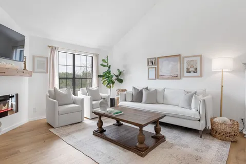 a living room with furniture a flat screen tv and a large window