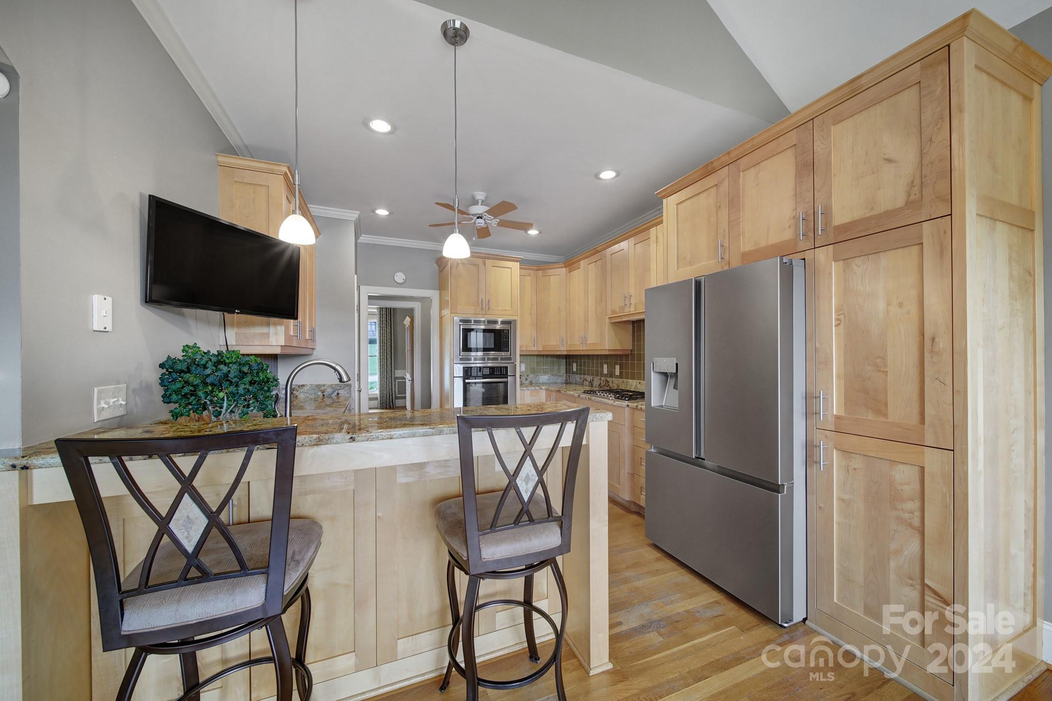 216 Edgewater Way Fort Mill, SC 29708 - Photo 17 of 45 a kitchen with stainless steel appliances a refrigerator a microwave oven a dining table and chairs with wooden floor