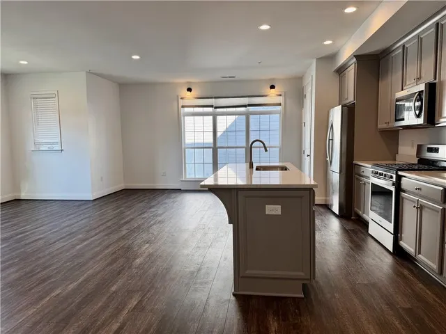 a kitchen with stainless steel appliances granite countertop a refrigerator a sink dishwasher a stove with wooden floors and cabinets