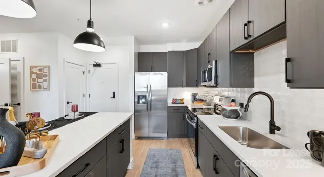 a kitchen with stainless steel appliances granite countertop sink stove and refrigerator