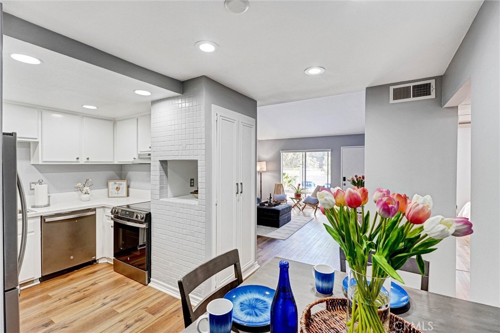 a kitchen with stainless steel appliances granite countertop a refrigerator a stove a sink dishwasher and white cabinets with wooden floor