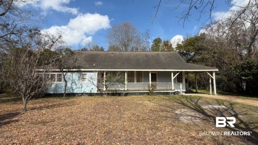 View of front of property with a large porch, a carport, and a front yard