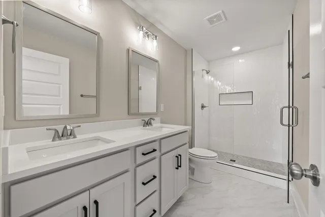 a bathroom with a double vanity sink toilet mirror and a shower