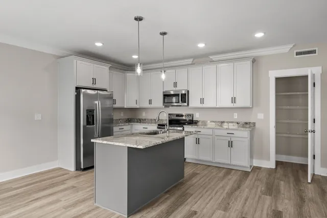 a kitchen with kitchen island white cabinets and stainless steel appliances