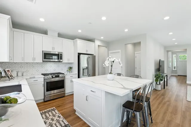 a kitchen with stainless steel appliances kitchen island granite countertop a sink a stove a dining table and chairs