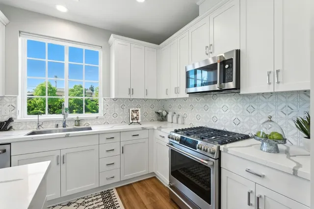 a kitchen with stainless steel appliances white cabinets granite counter tops and a window