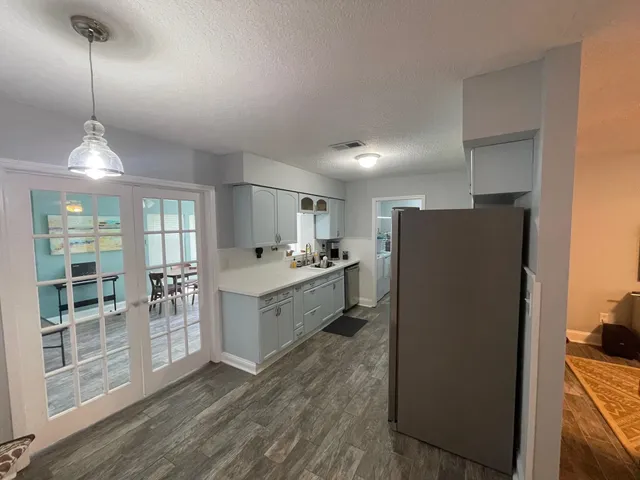 a large kitchen with a refrigerator a sink dishwasher a oven and a dining table with wooden floor