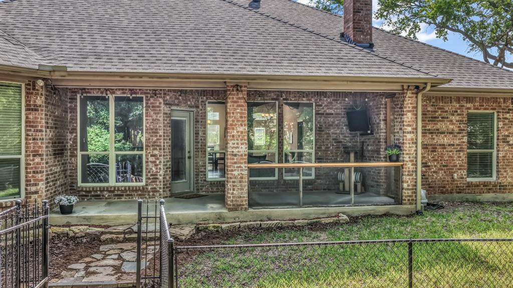 203 Mockingbird Lane Aledo, TX 76008 - Photo 35 of 37 Brick exterior featuring a covered patio, multiple windows, and a fenced yard with a stone path
