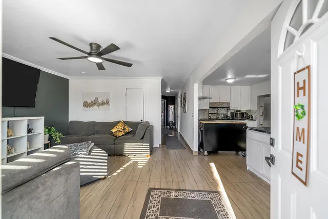 a kitchen with stainless steel appliances granite countertop a stove top oven a sink dishwasher a refrigerator and white cabinets with wooden floor