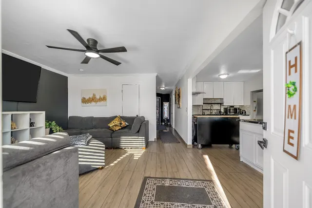 a living room with furniture ceiling fan and a large window