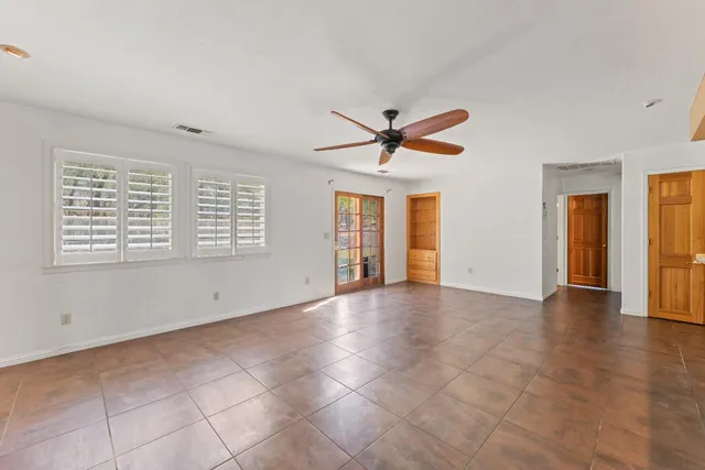a view of an empty room with window and a chandelier fan