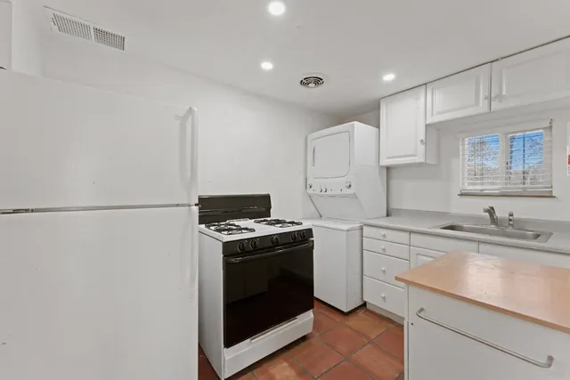 a backyard of a house with large trees and brick wall