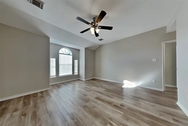 a view of empty room with wooden floor and ceiling fan