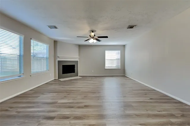 a view of an empty room with window and wooden floor
