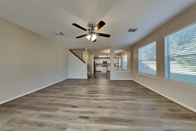 a view of empty room with wooden floor and fan