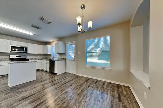 a kitchen with granite countertop a stove a sink dishwasher a refrigerator and a fireplace with wooden floor