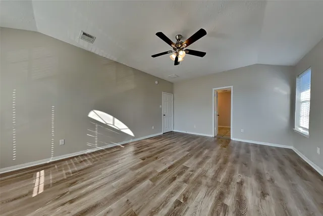 a view of empty room with wooden floor and ceiling fan