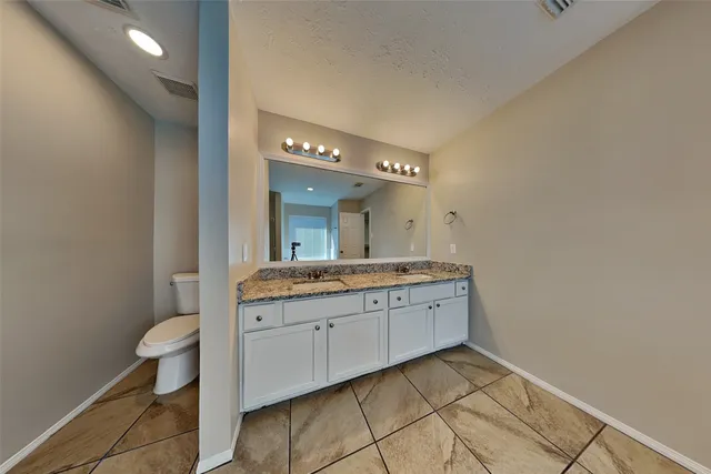 a spacious bathroom with a granite countertop sink a toilet and a mirror