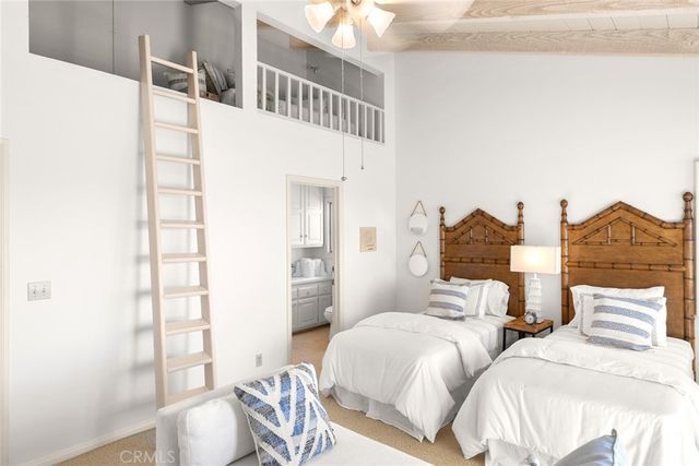 a bedroom with two beds and next to a window