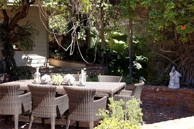 a view of a patio with table and chairs potted plants and large tree
