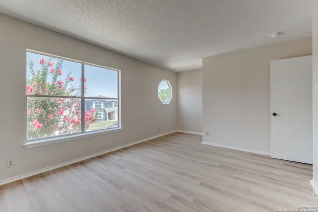 a view of an empty room with window and wooden floor