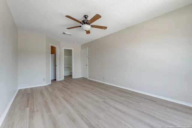 an empty room with wooden floor and a ceiling fan
