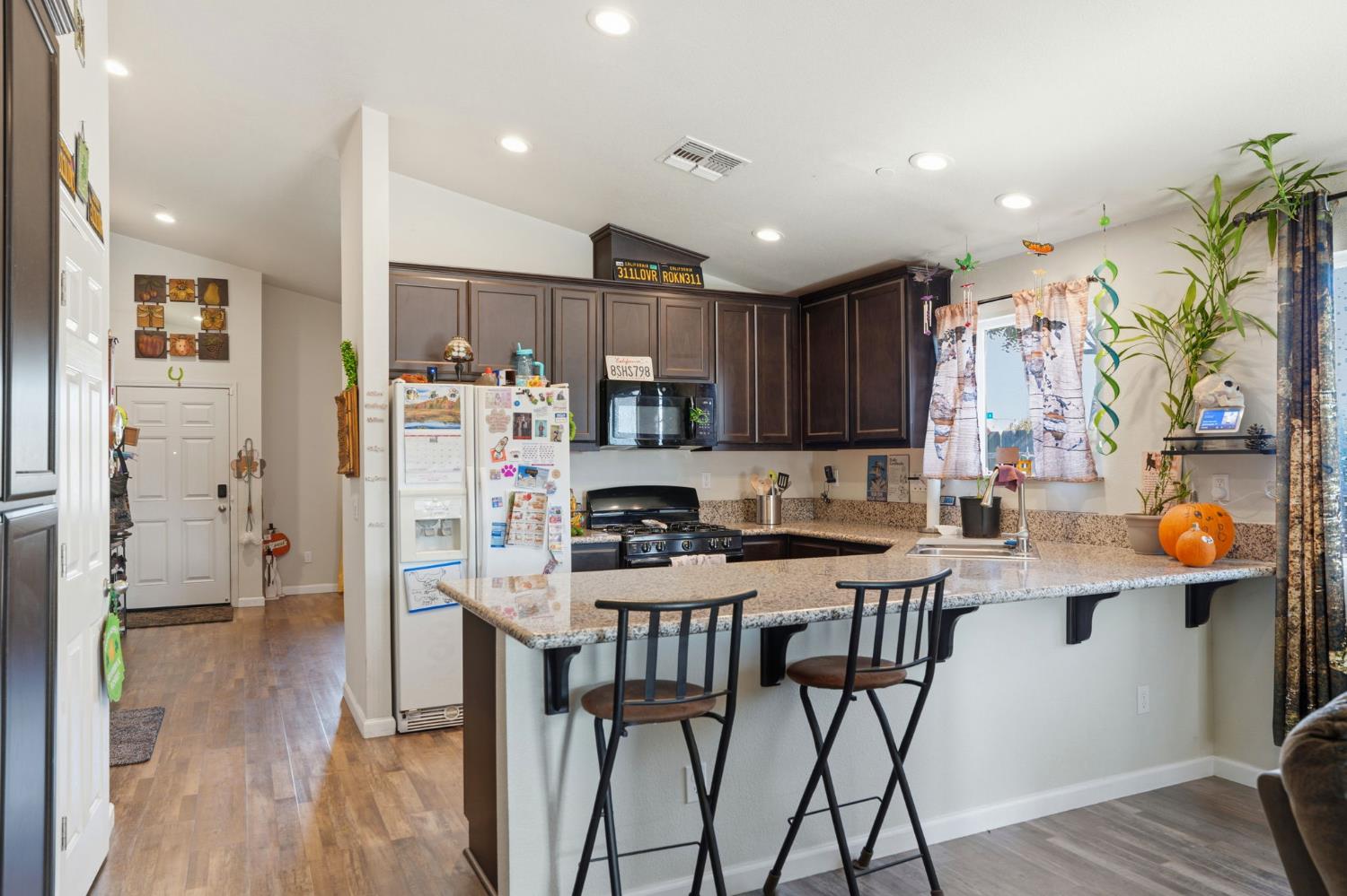296 Dena Court Merced, CA 95341 - Photo 10 of 34 a kitchen with stainless steel appliances kitchen island granite countertop a table chairs refrigerator and microwave
