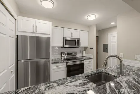 a kitchen with granite countertop a refrigerator stove and sink