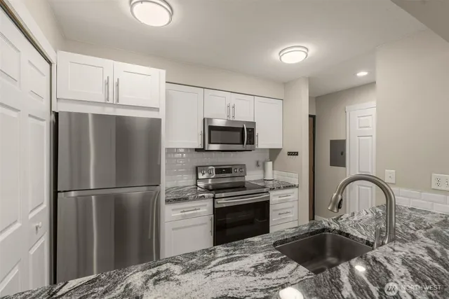 a kitchen with granite countertop a refrigerator stove and sink