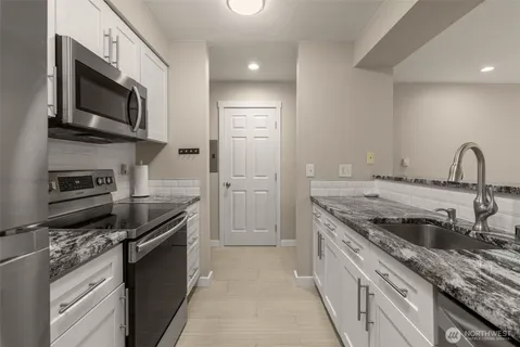 a kitchen with stainless steel appliances granite countertop a stove a sink and a microwave