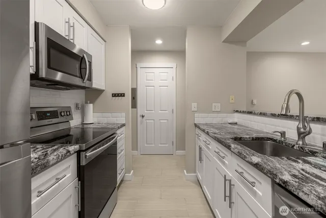 a kitchen with stainless steel appliances granite countertop a stove a sink and a microwave