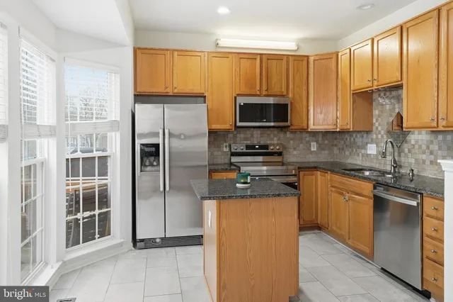 a kitchen with granite countertop a refrigerator a sink a stove top oven and cabinets