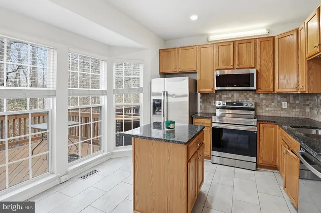 a kitchen with kitchen island granite countertop a stove top oven a sink and a refrigerator