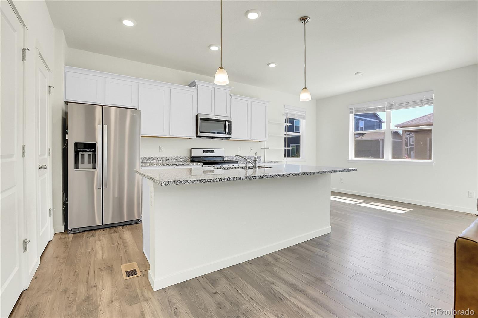 45840 Laceleaf Drive Bennett, CO 80102 - Photo 12 of 43 a kitchen with kitchen island a refrigerator a stove a sink and a oven with wooden floor