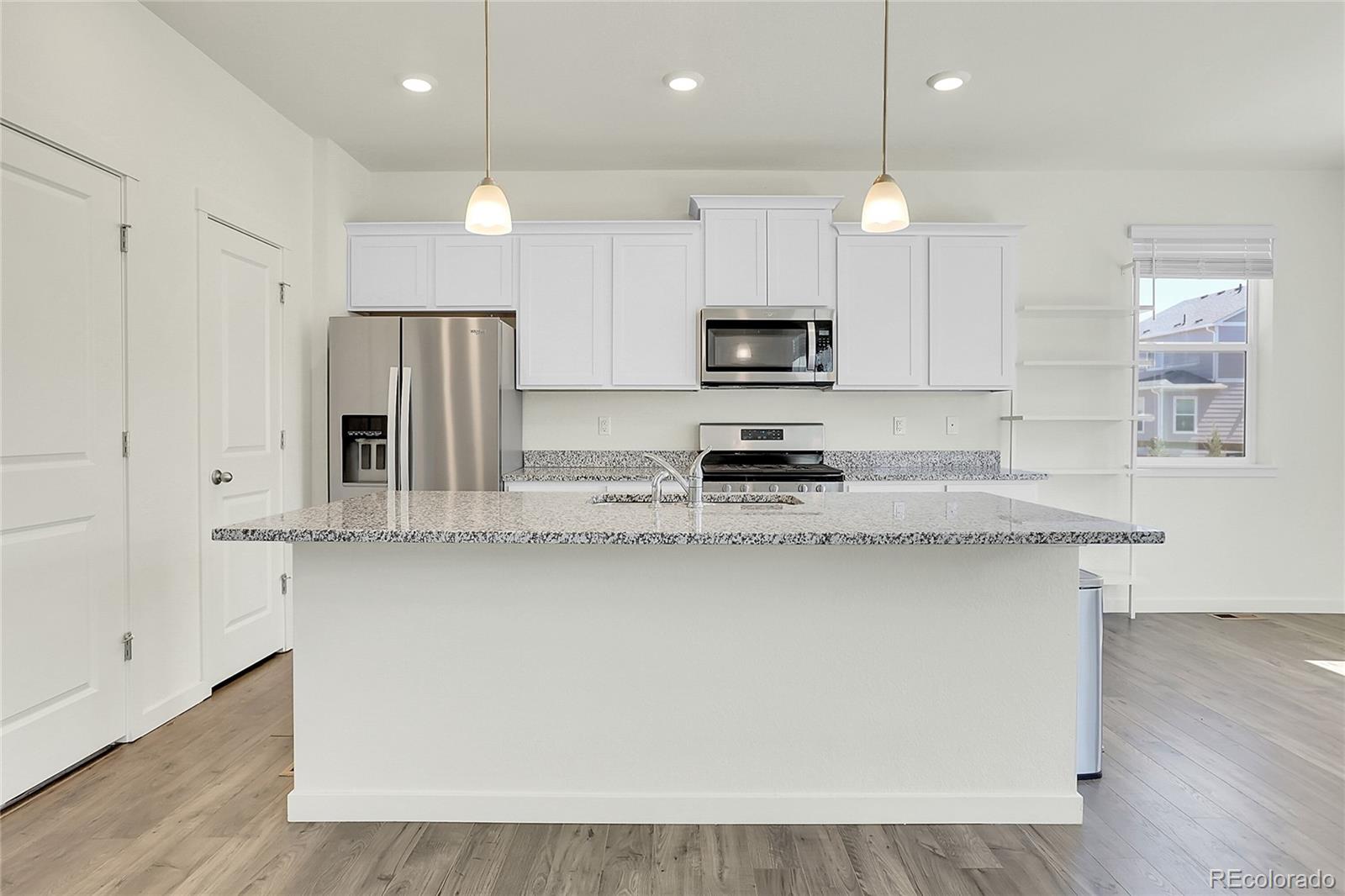 45840 Laceleaf Drive Bennett, CO 80102 - Photo 13 of 43 a large kitchen with stainless steel appliances a large counter top a stove a sink cabinets and a wooden floor