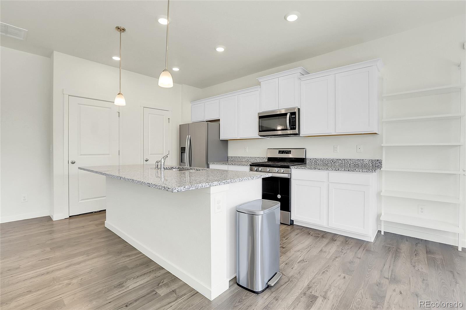 45840 Laceleaf Drive Bennett, CO 80102 - Photo 14 of 43 a kitchen with kitchen island white cabinets and stainless steel appliances