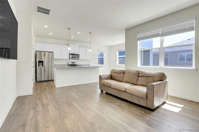 a kitchen with kitchen island a refrigerator a stove a sink and a oven with wooden floor