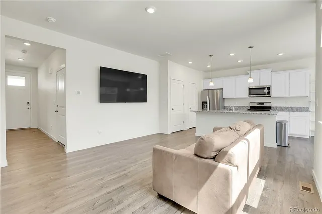 a large kitchen with stainless steel appliances a large counter top a stove a sink cabinets and a wooden floor