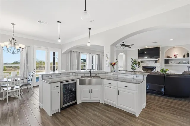a kitchen with stainless steel appliances granite countertop hardwood floor sink stove dining table and chairs