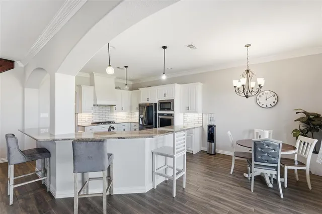 a kitchen with kitchen island stainless steel appliances a dining table chairs and wooden floor