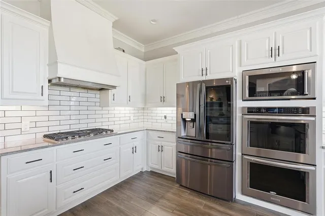 a kitchen with cabinets stainless steel appliances and wooden floor