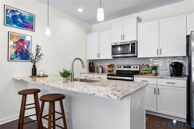 a kitchen with stainless steel appliances granite countertop a stove a sink and a microwave