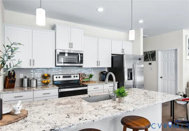 a kitchen with stainless steel appliances granite countertop a sink a stove a refrigerator and a dining table with wooden floor