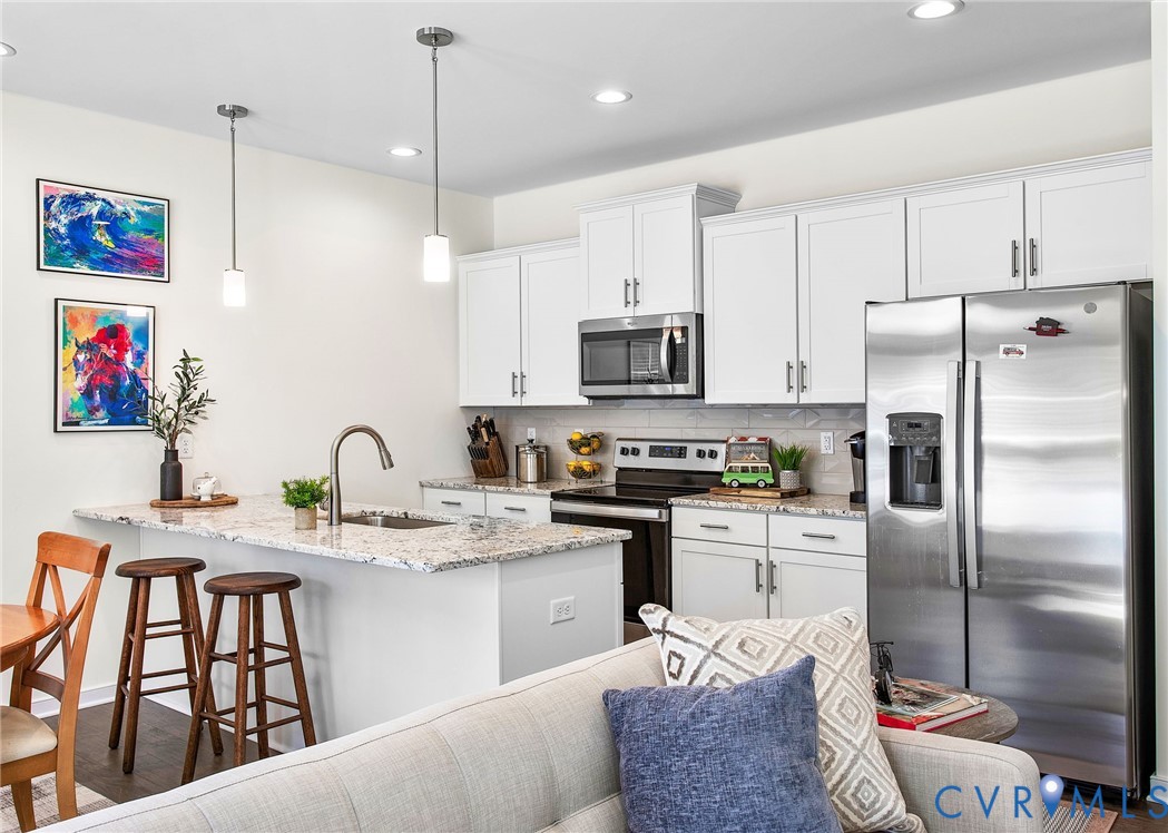6549 Bolles Landing Court Chester, VA 23831 - Photo 10 of 22 a kitchen with stainless steel appliances kitchen island granite countertop a refrigerator a sink a stove and white cabinets