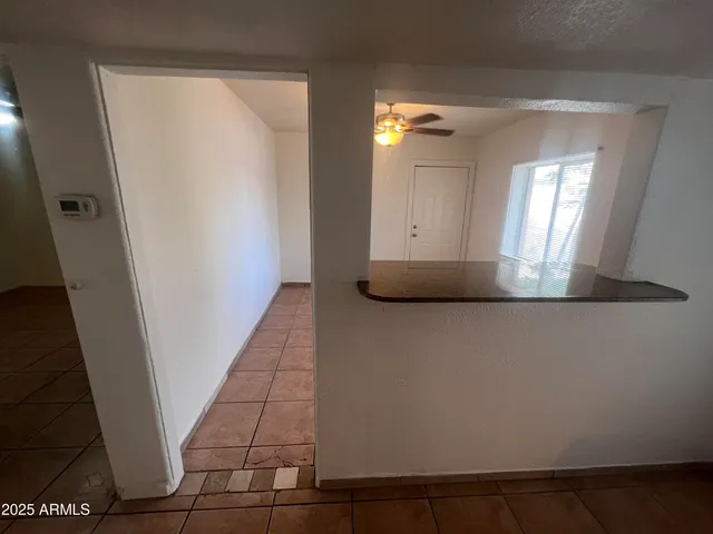a view of an empty room and chandelier fan