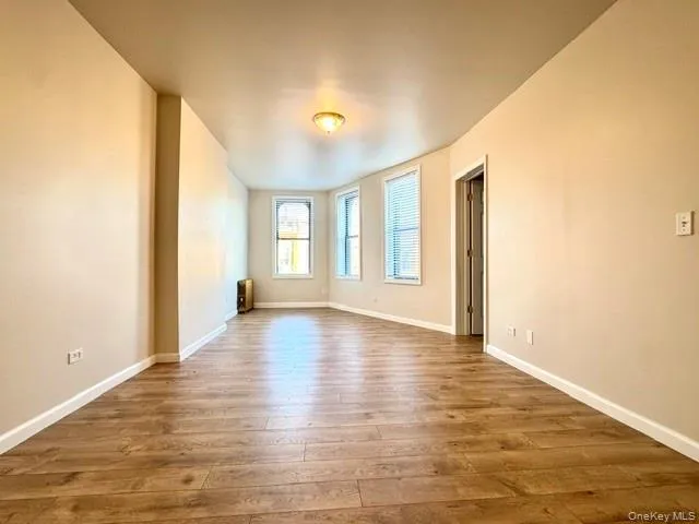 a view of an empty room with window and wooden floor