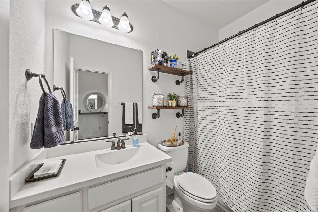 813 Pier Street Little Elm, TX 76227 - Photo 12 of 16 a bathroom with a sink a toilet a mirror and shower curtain