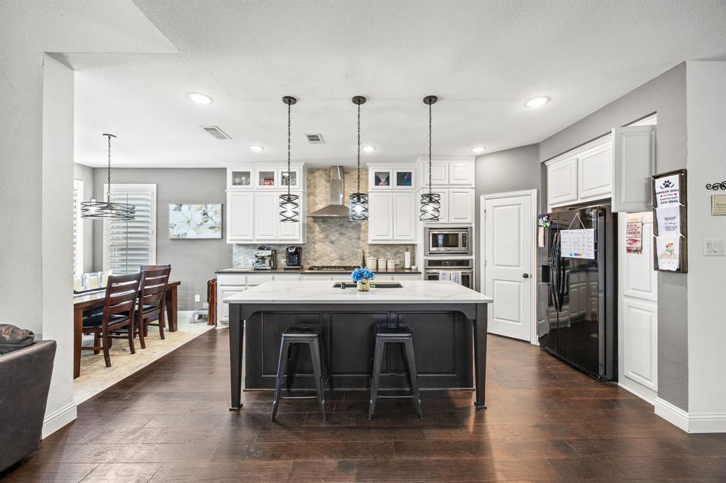 813 Pier Street Little Elm, TX 76227 - Photo 5 of 16 a kitchen with stainless steel appliances kitchen island granite countertop a table chairs and a refrigerator