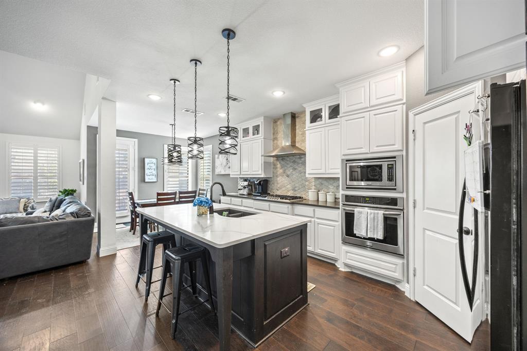 813 Pier Street Little Elm, TX 76227 - Photo 6 of 16 a kitchen with stainless steel appliances a stove a sink a refrigerator white cabinets and couches